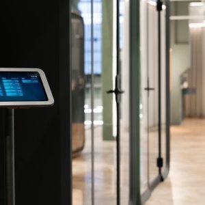 Framery One Compact in dunkler Ausführung neben Schreibtischen